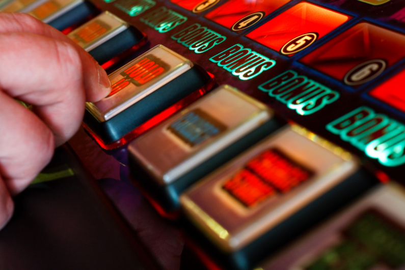 Finger pressing the hold button on slot machine