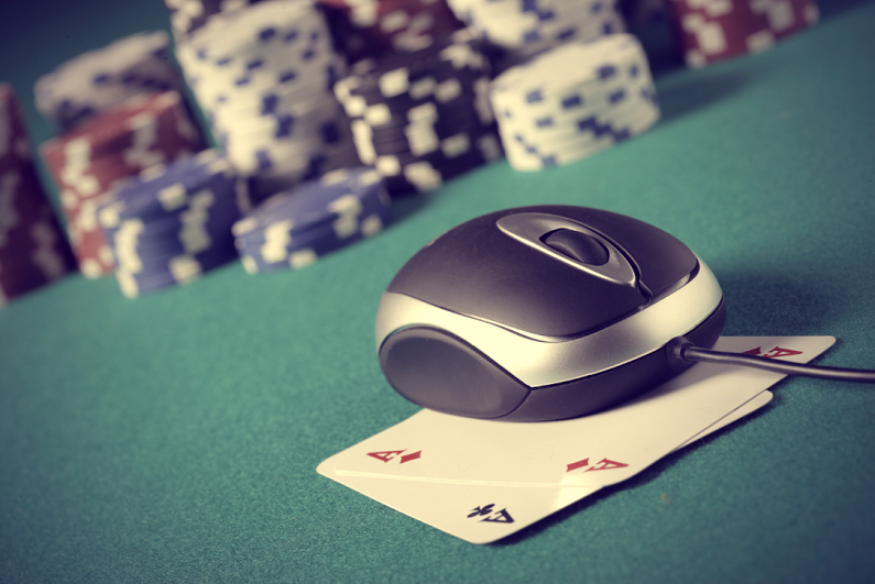 computer mouse sitting on top of playing cards with poker chips in background