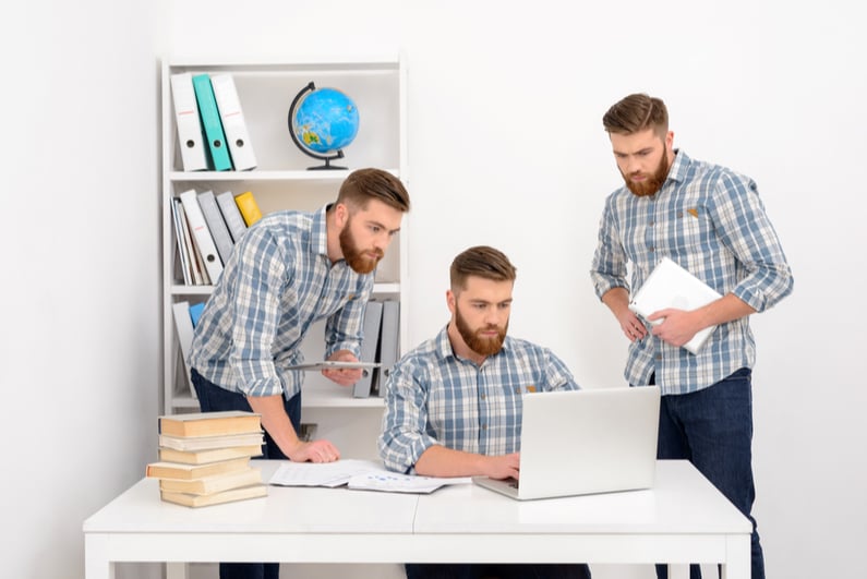 Three male clones looking at a laptop