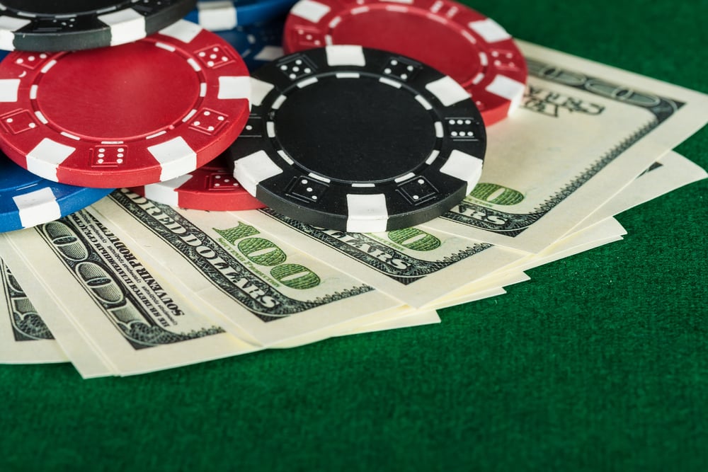 poker chips and hundred-dollar bills on green poker table